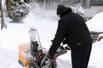 Man snow blowing driveway after blizzard. 