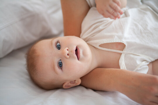 Little newborn baby lies on a white fluffy bedspread.
