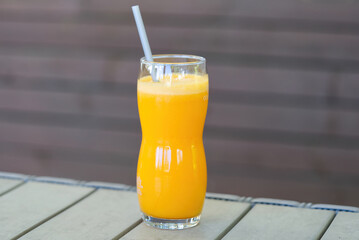 a glass of orange juice on a table at an outdoor bar close up
