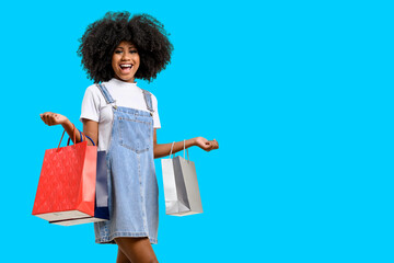  woman holds shopping bags, teen girl smiles and looks at camera, on blue background.