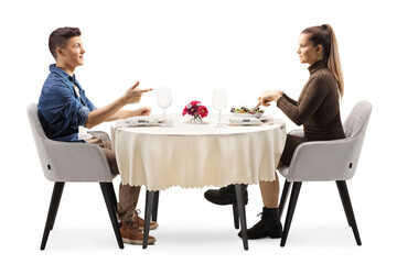 Profile shot of a young man and woman sitting at a restaurant table and talking - Powered by Adobe