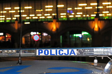 Sygnalizator błyskowy niebieski na dachu radiowozu policji polskiej w nocy na drodze. 
