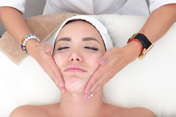 Facial treatment that allows women to rejuvenate. Dermatologist applies a facial treatment to a young white woman, who is lying in a clinic specializing in skin rejuvenation.
