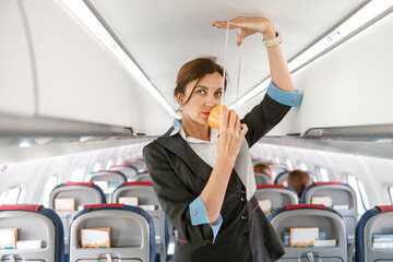 Female stewardess demonstrating how to use oxygen mask in plane