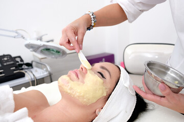 Facial treatment that allows women to rejuvenate. Dermatologist applies a facial treatment to a young white woman, who is lying in a clinic specializing in skin rejuvenation.