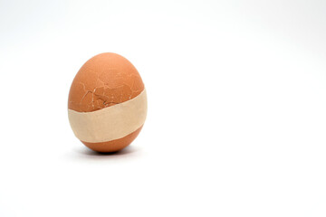 Chicken egg with a crack and a tape stuck on it, the concept of treatment and healthcare. Medical...