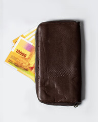 10000 Comorian franc notes inside a purse. Comorian currency popping out of a brown leather purse