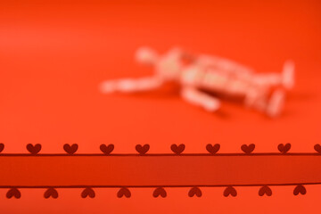Red ribbon with hearts in focus. Couple making love out of focus. Juicy red background. Adult...