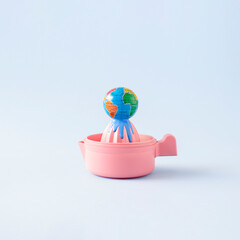 Globe or planet earth squeezed on a pink lemon squeezer. Creative composition of global abuse of...