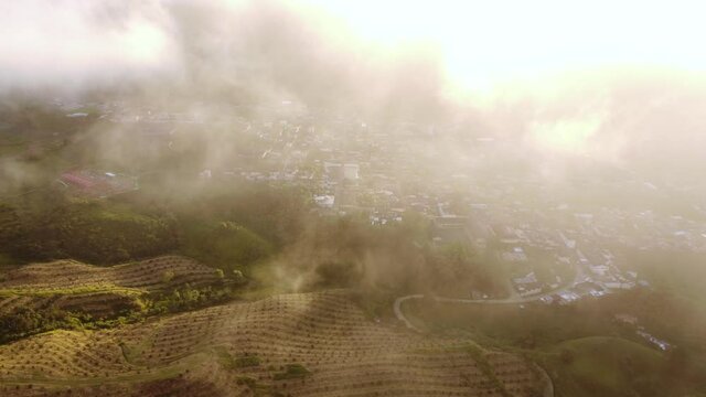 aerial shot reveals village through the clouds in the middle of the mountains. artistic sunflare, Versalles Valle - Colombia