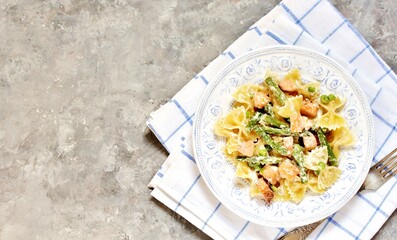 pasta farfalle with salmon and asparagus in a creamy sauce, in a beautiful plate,  top view 