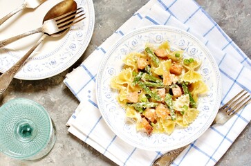 pasta farfalle with salmon and asparagus in a creamy sauce, in a beautiful plate,  top view 