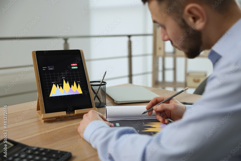 Poster forex trader working with tablet and chart in office