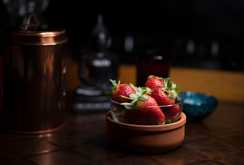 Natural fresh juicy strawberries in a glass - ceramic bowl on wooden table with a soft light.