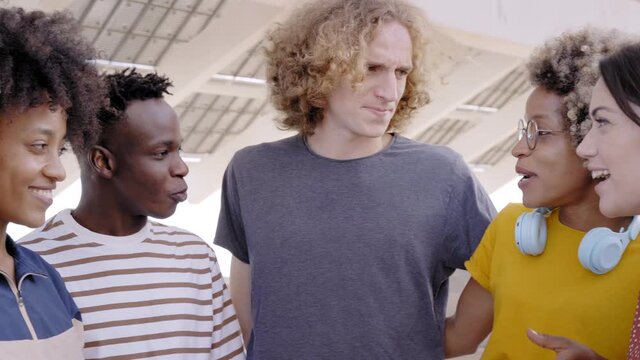 Group of young friends having fun outdoors. People of mixed races spending time together. The boys look at each other and laughing