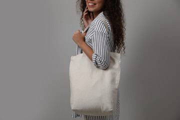Happy African-American woman with eco bag on grey background, closeup