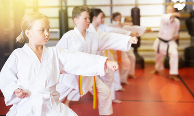 Obraz premium Children wearing karate uniform practicing new moves in group at gym