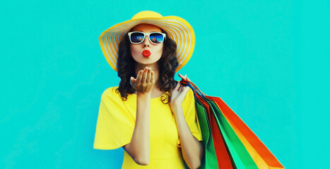 Portrait of beautiful happy young woman with shopping bags wearing summer straw round hat on blue background