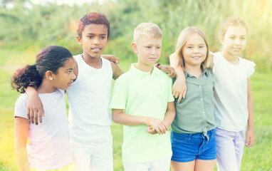 African-american and European children standing on grass outdoors.