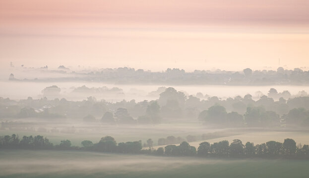 Misty view from Chilterns over oxfordshire at dawn sunrise with soft colours and layers