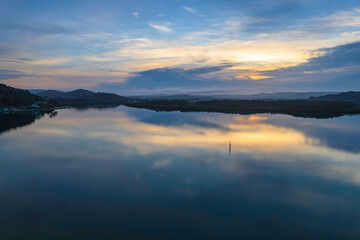 Soft and peaceful sunrise aerial waterscape with clouds and reflections