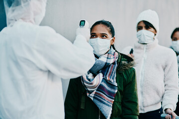 Here to keep the citizens safe. Shot of a young woman getting her temperature taken with an...
