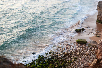 Rocky beach with waves at sunset from above