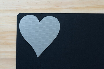 silver paper heart on black paper and wood
