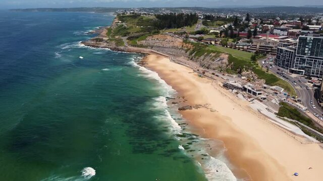 Aerial drone shot of sandy Newcastle Beach waves and city CBD lookout tourism Pacific Ocean NSW Australia 4K
