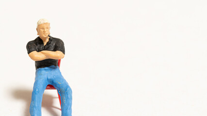椅子に座って腕を組みこちらをみている男性の人形