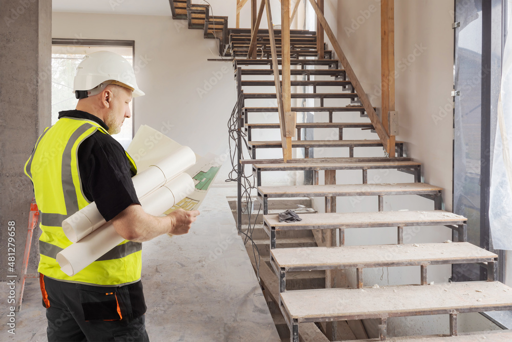 Aufkleber builder inside house under construction. engineer with drawings in his hands. man is considering a h