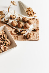 Cosy autumn aesthetic composition with dry  leaves, walnuts on white background. Flat lay, top view, copy space.