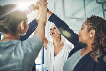 Obraz premium Success is shining on this team. Shot of a diverse group of coworkers high fiving together in an office.