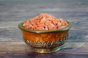 Pink Himalayan salt in Antique Tibetan bowl on wooden table. Selective focus with copy space