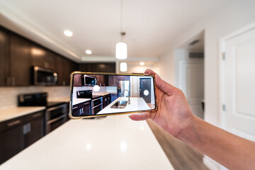 Hand photographing house apartment kitchen island room for sale or rent with phone smartphone closeup point of view in modern luxury condo home with blurry bokeh background - obrazy, fototapety, plakaty
