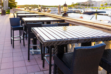 Naples, Florida nobody empty outdoor restaurant cafe patio sunny sunset sunlight by marina dock wharf near Bayfront place with seating chairs tables by railing on street road sidewalk