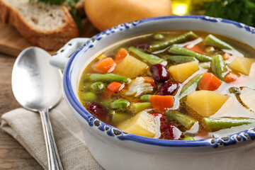 Bowl of tasty turnip soup with napkin and spoon on table, closeup