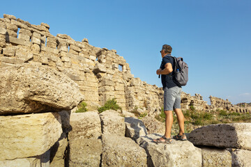 Tourist with backpack looking at Side ancient city, Turkey. Summer vacation. Historical trip.