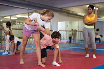 Fototapeta na wymiar Positive teenager kids in pair exercising self-defense movements during group class