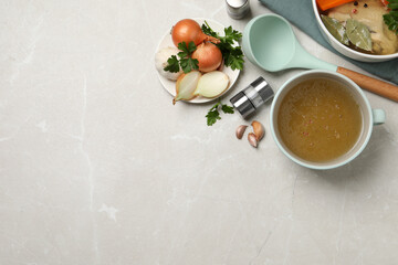 Fototapeta na wymiar Hot delicious bouillon and ingredients on light grey table, flat lay. Space for text