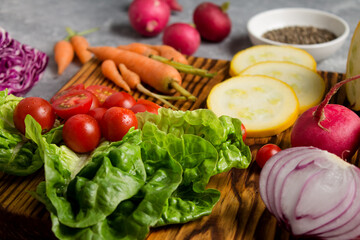 wooden board with fresh, eco, organic vegetables on gray background