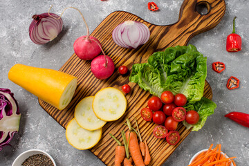 wooden board with fresh, eco, organic vegetables on gray background