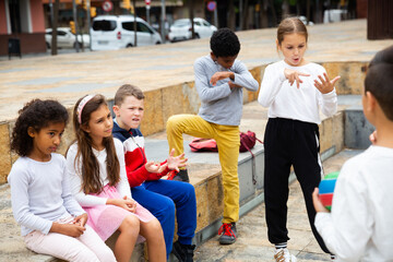 Obraz premium Group of happy tweenagers of different nationalities hanging out on streets of city on warm spring day.