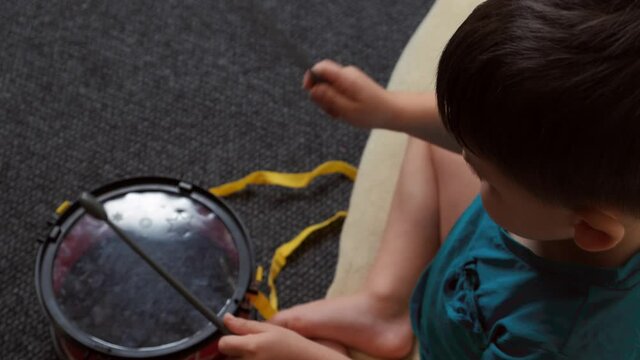 Caucasian little boy playing at drums sitting on the floor. Child developement
