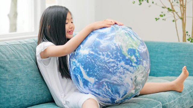 地球模様のボールで遊ぶ女の子　エコロジーイメージ　SDGs