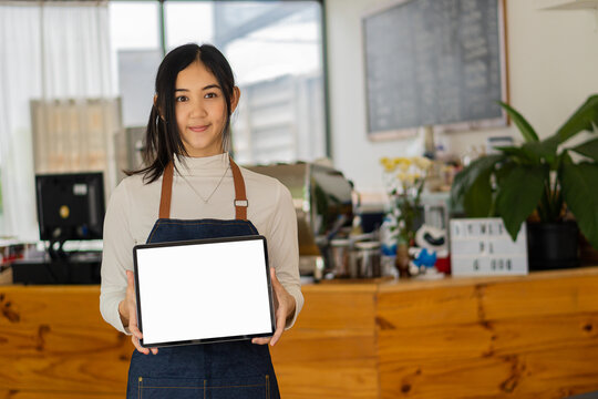 Asian woman holding a tablet with a white or blank screen that can insert text as she pleases and presenting something product presentation