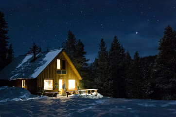 Starry skies over a cabin at night in the snowy mountains - Powered by Adobe