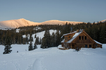 Sunrise over a snowy mountain cabin in winter
