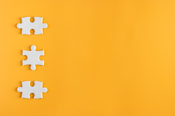 Top view of three piece jigsaw puzzle on yellow or orange background. plain blank empty space for...