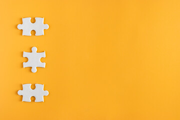 Top view of three piece jigsaw puzzle on yellow or orange background. plain blank empty space for copy space. business concept.